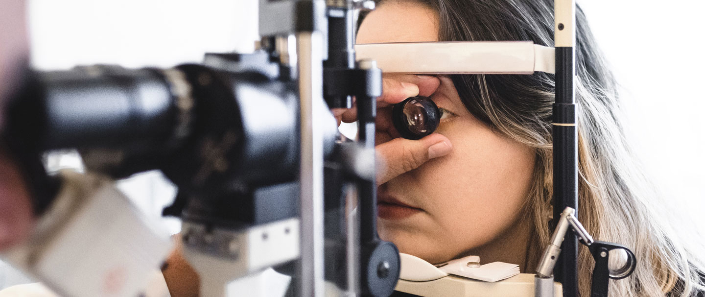 A woman having her eyes closely examined by a medical professional