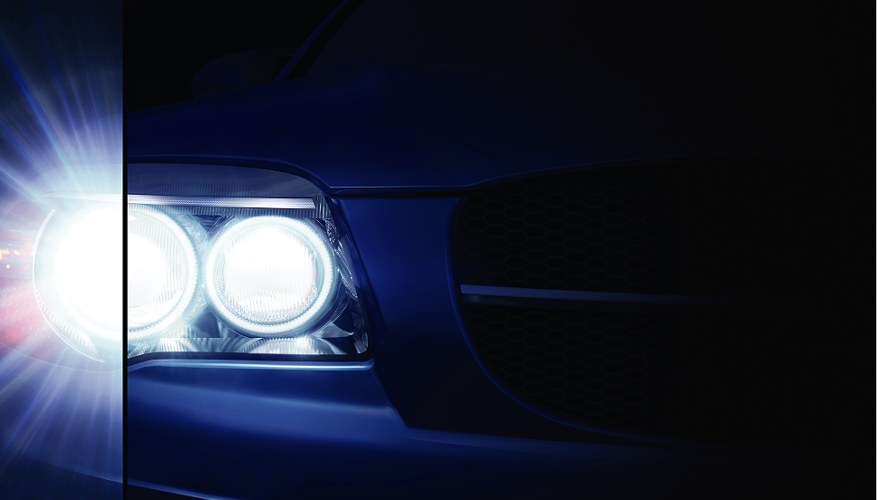 Een close-up van de koplamp aan de passagierskant van een auto die het donker verlicht. Een verticale lijn verdeelt de koplamp in tweeën, met een stervormig effect op het licht aan de linkerkant van de lijn. 