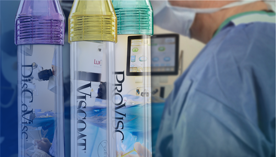 Een close-up van drie buisjes met Alcon Ophthalmic Viscosurgical Devices. De tube met de paarse dop draagt de naam DisCoVisc, de tube met de gele dop draagt de naam VISCOAT en de tube met de groene dop draagt de naam PROVISC. Achter de buisjes staat een chirurg met een medisch masker en operatiekleding op.