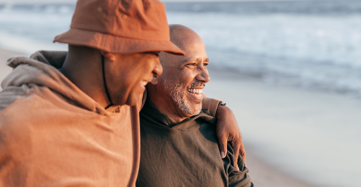 Father and adult son laughing and sharing a moment at the beach