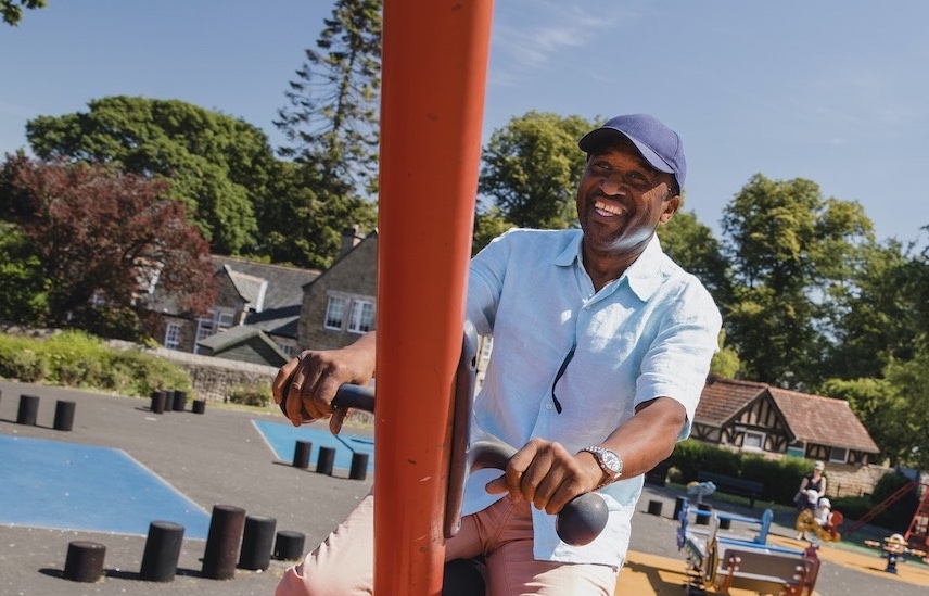 Smiling man in park on a swing set