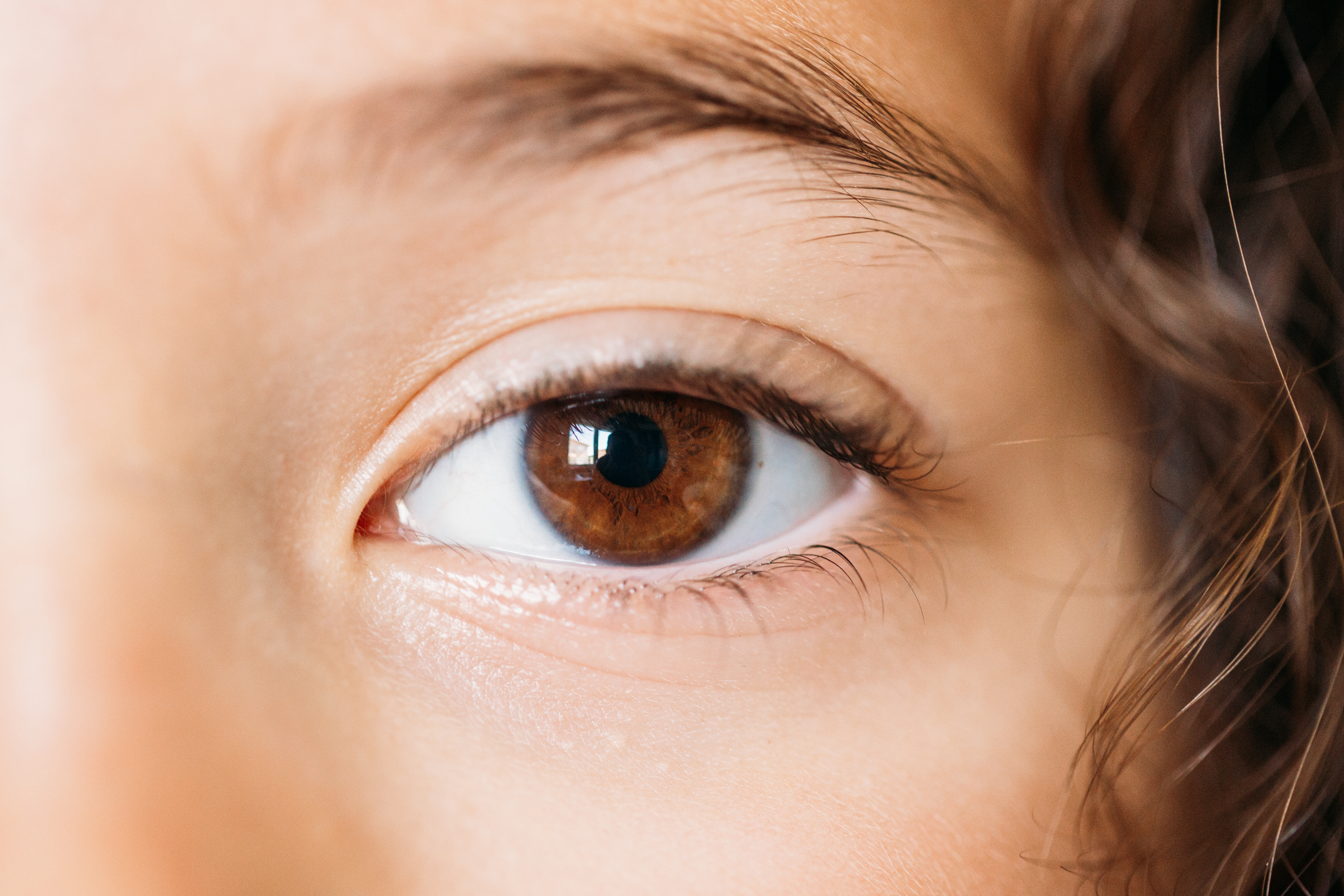 Close up image of child's eye with brown iris and brown curly hair