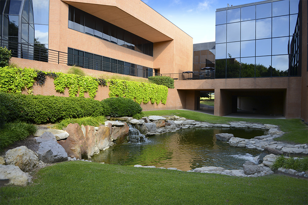 View of a stone-lined pond with green landscaping outside the Fort Worth, Texas office