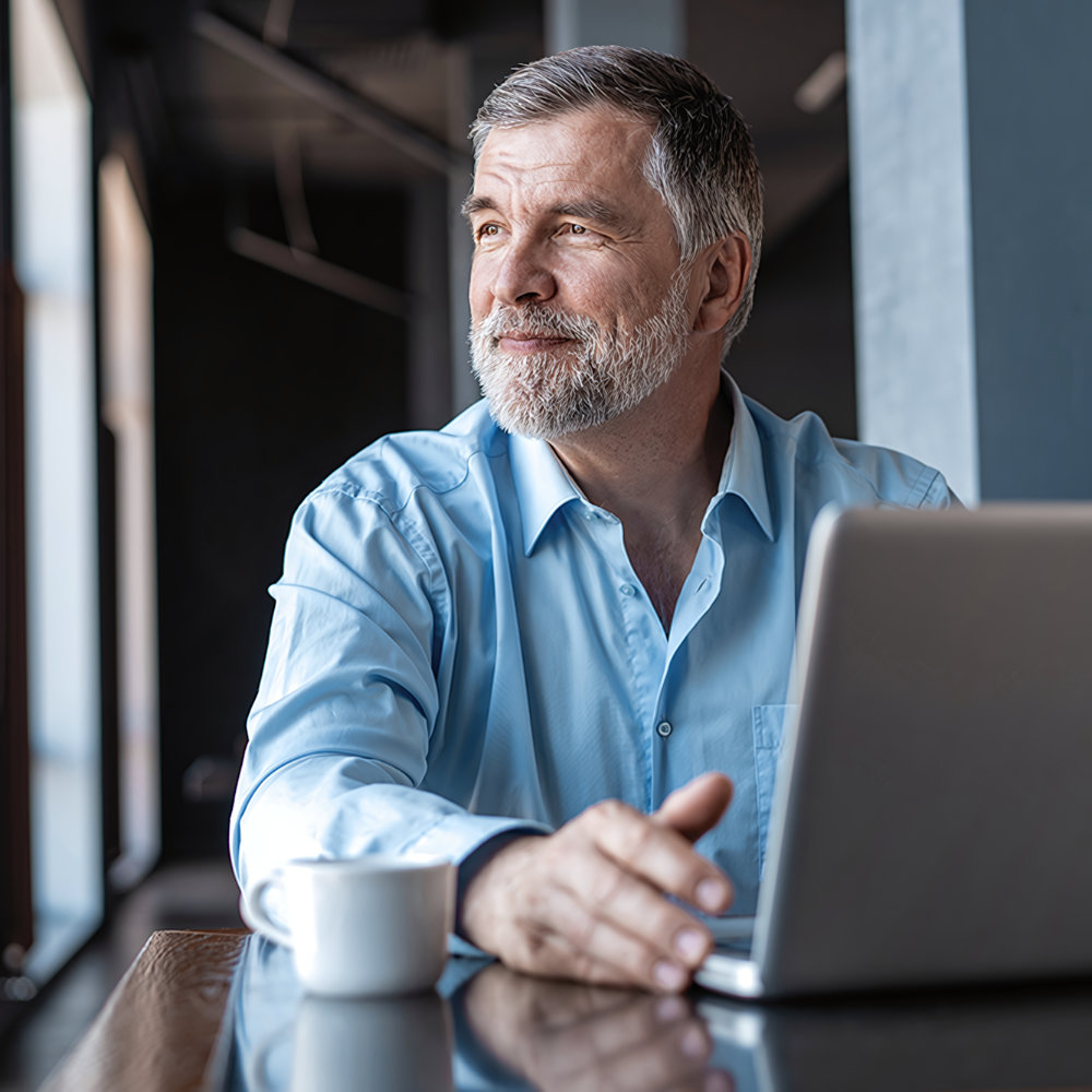 An older gentleman in a blue shirt is looking off into the distance