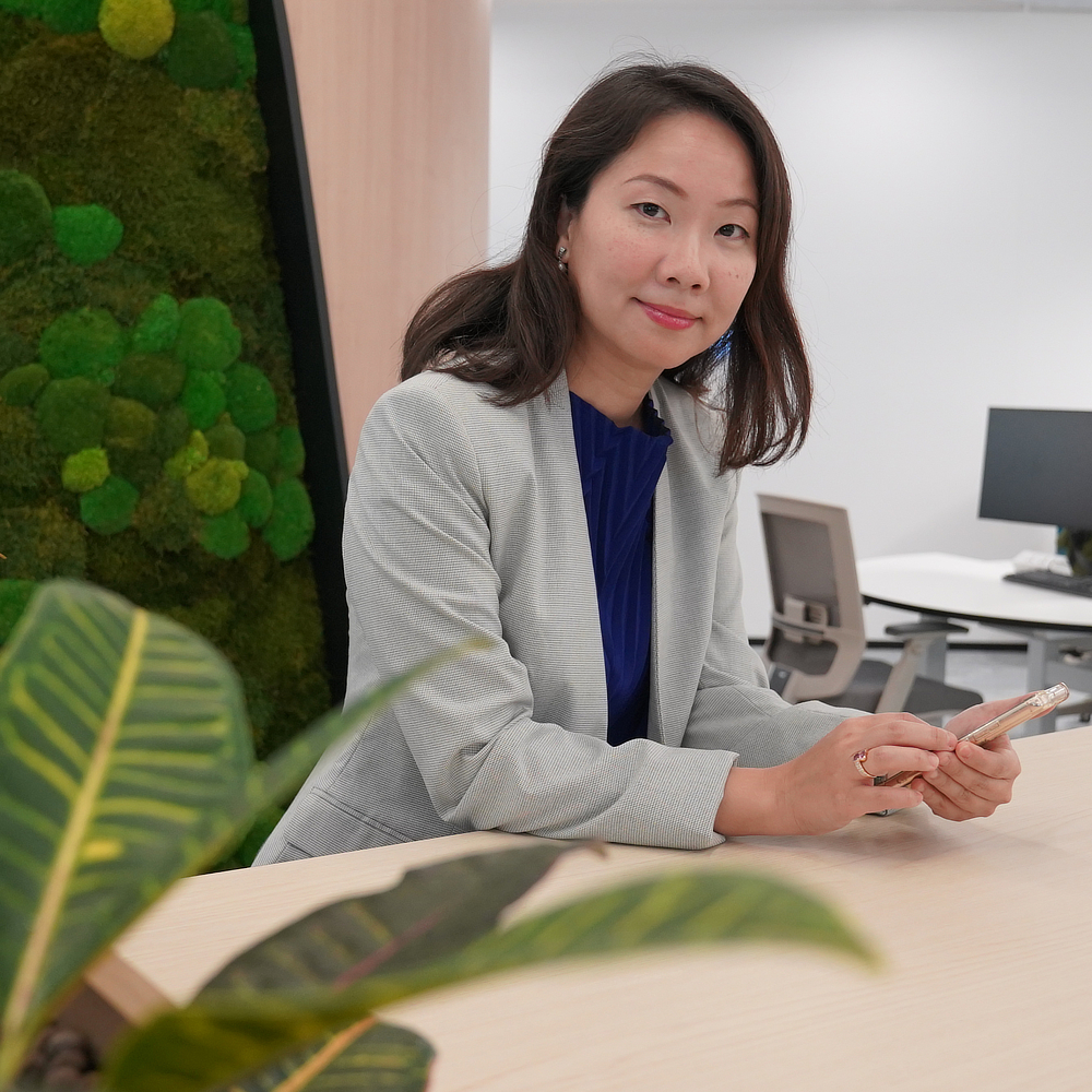 Businesswoman looking at the camera while operating a smartphone.