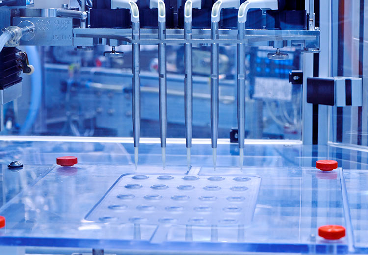 Nahaufnahme einer hochentwickelten Labormaschine in Blautönen mit mehreren Metalldüsen über einer durchsichtigen Plattform mit kleinen runden Vertiefungen, die Präzision vermitteln.