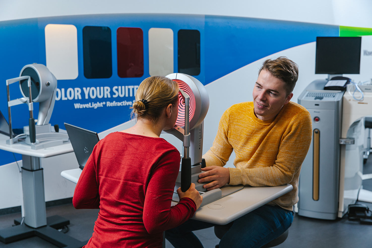 Eine junge Frau lässt sich von einem jungen Mann mit dem Wavelight Topolyzer VARIO die Augen vermessen.