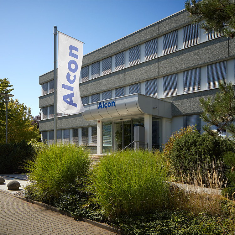 Außenansicht des WaveLight Bürogebäudes von Alcon in Erlangen, Deutschland, mit Firmenflagge am Eingang.