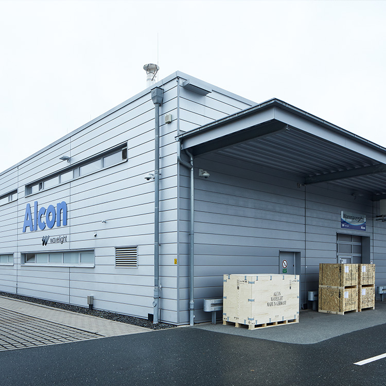 Außenansicht des Alcon WaveLight Standorts in Pressath, Deutschland, mit Ladebereich und Versandkisten.