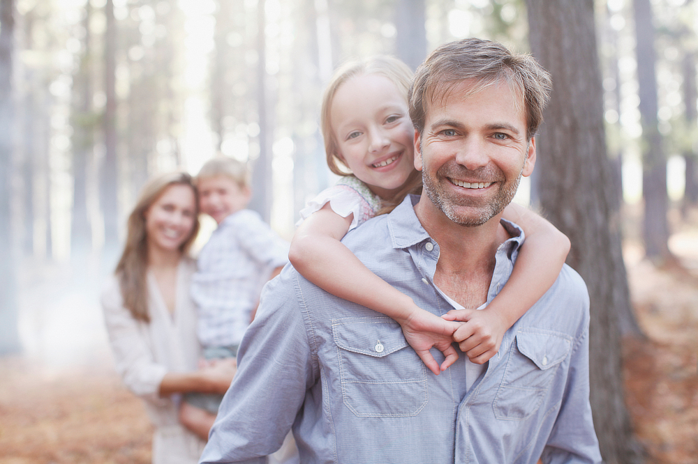 A young family in a forest smiling at the camera
