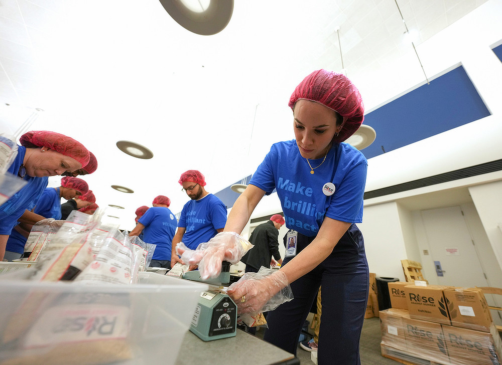 Employees in blue t-shirts and hair nets packing food