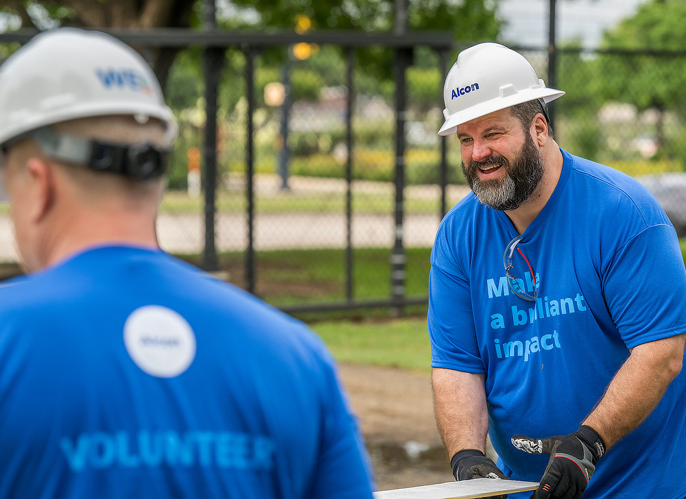 Two men working in blue t-shirts and hard hats.