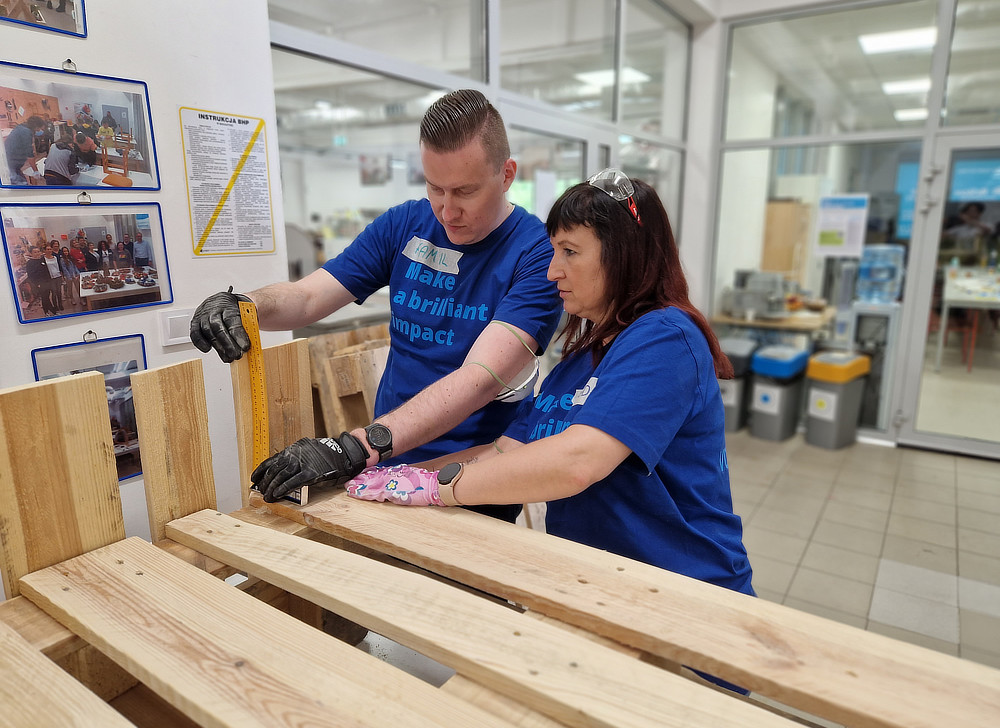 Employees in blue t-shirts building shelving