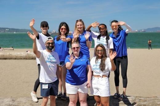 Group of volunteers on beach waving at camera