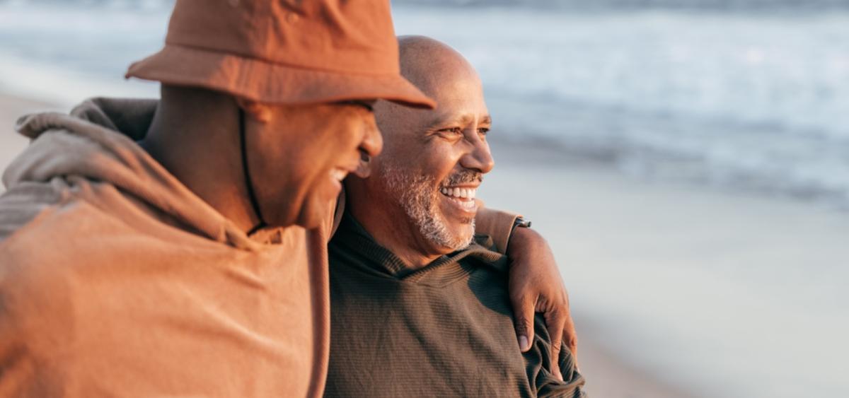 Father and adult son laughing and sharing a moment at the beach