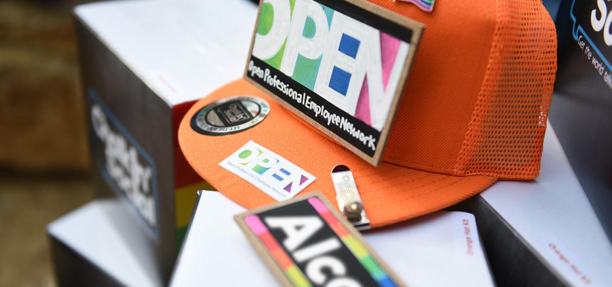 Close-up of ball cap with OPEN logos and Pride flag pin