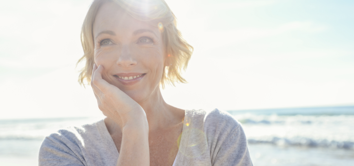 Portrait of a smiling woman on beach with sun in background