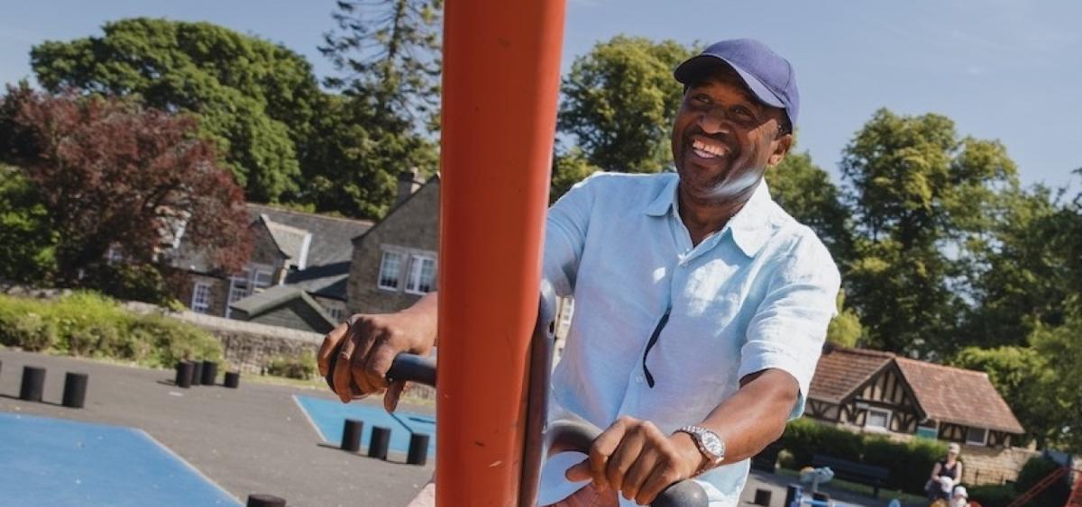 Smiling man in park on a swing set
