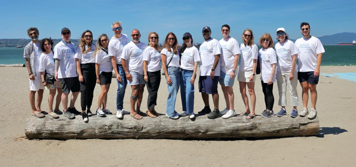 Group of volunteers standing on large piece of driftwood on beach