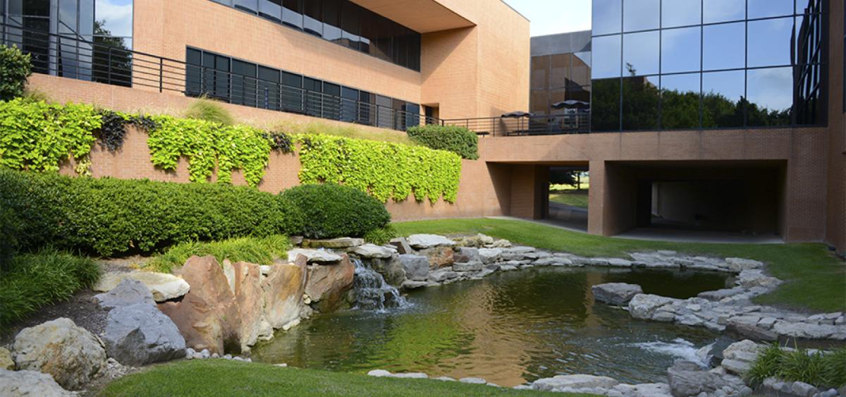 View of a stone-lined pond with green landscaping outside the Fort Worth, Texas office