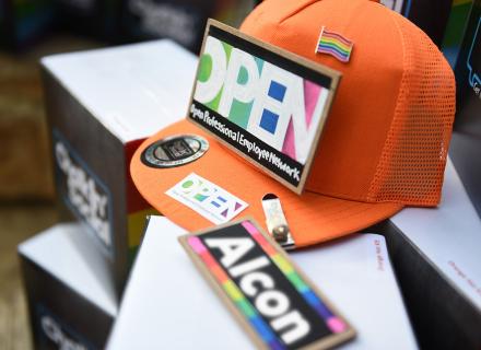 Close-up of ball cap with OPEN logos and Pride flag pin