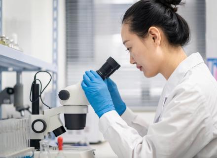 Woman in lab looking into microscope