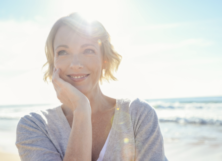 Portrait of a smiling woman on beach with sun in background