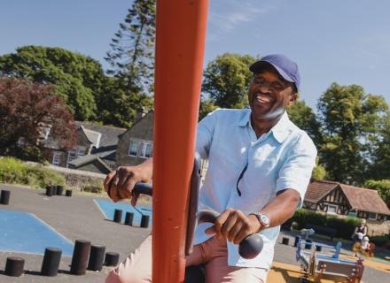 Smiling man in park on a swing set