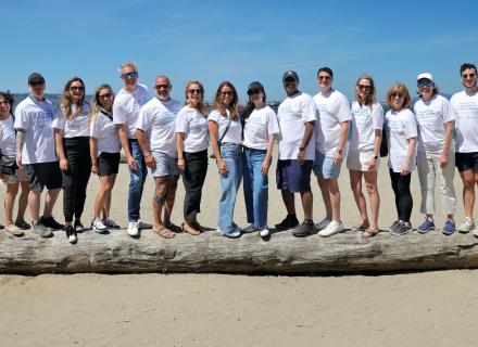 Group of volunteers standing on large piece of driftwood on beach