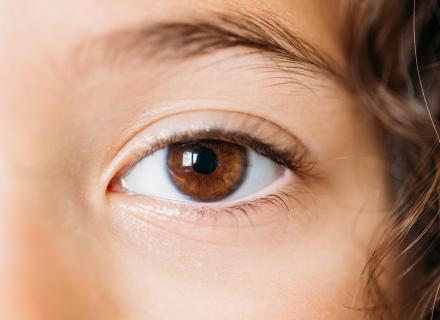 Close up image of child's eye with brown iris and brown curly hair