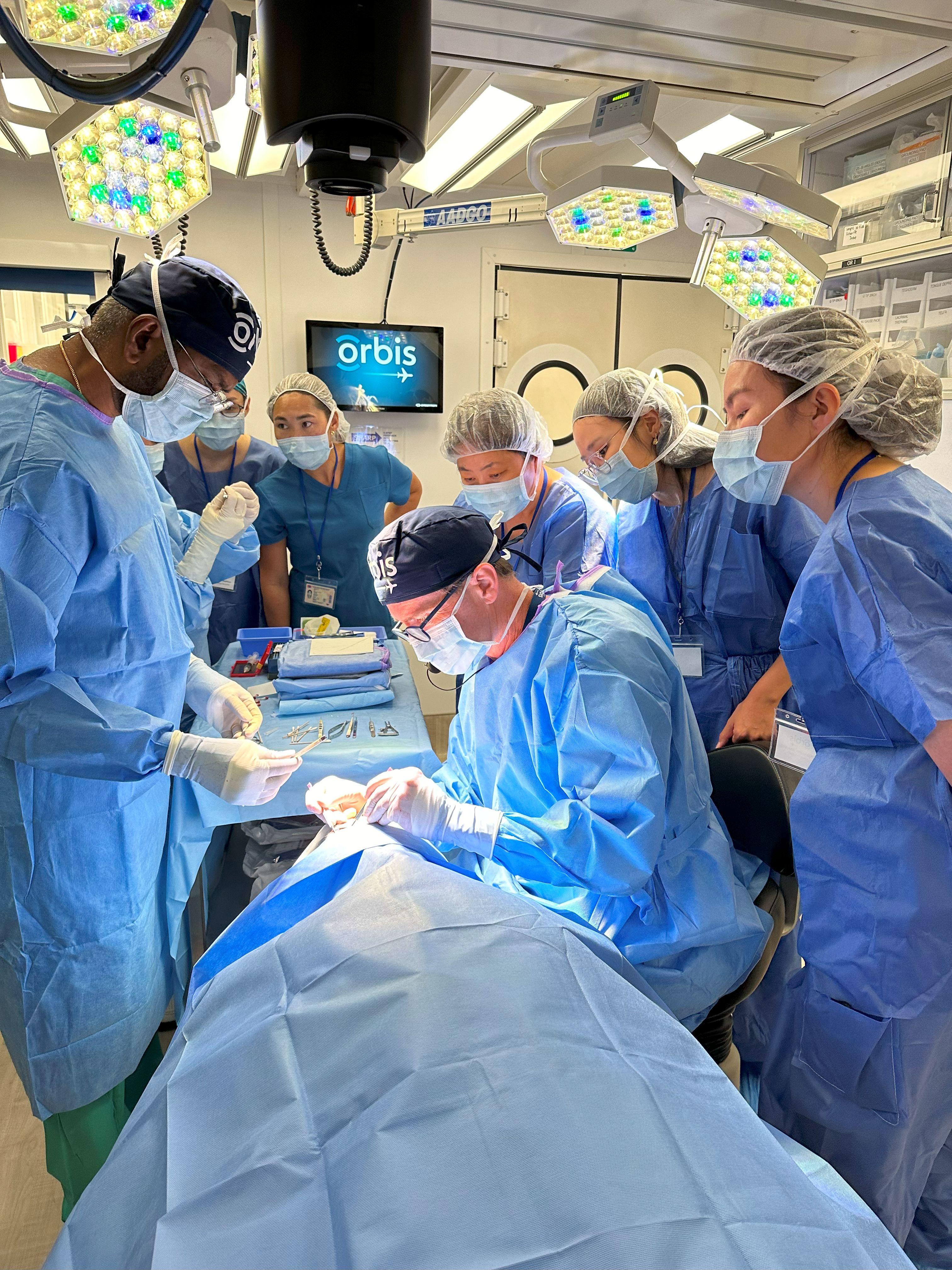 Group of medical professionals in scrubs and masks observing a surgical procedure