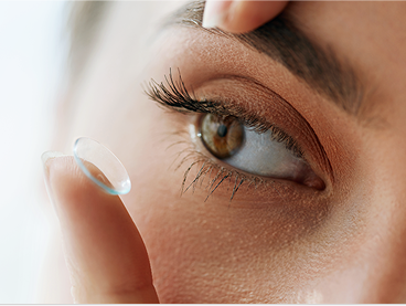 Close-up of a person’s eye as they prepare to insert a contact lens using their index finger
