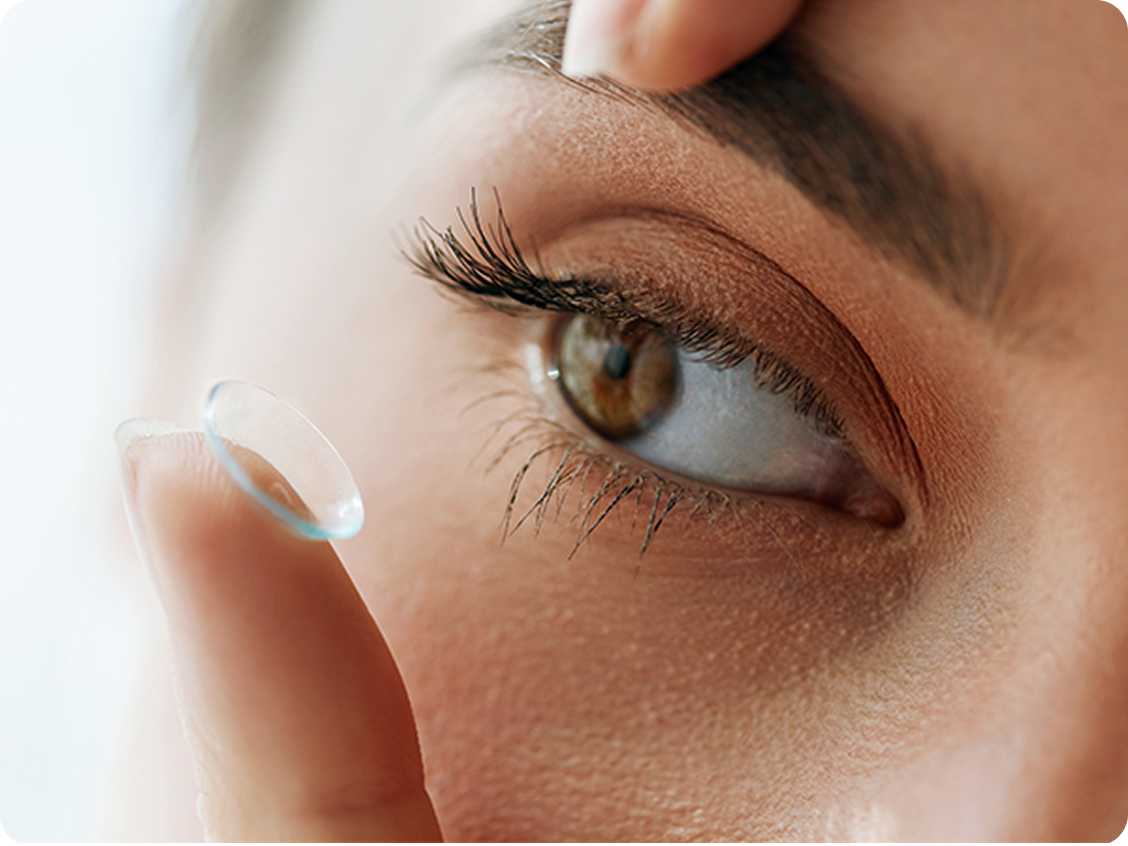 Close-up of a person’s eye as they prepare to insert a contact lens using their index finger