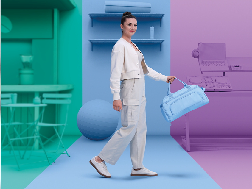 Woman walking confidently across a color-blocked background, holding a light blue duffel bag