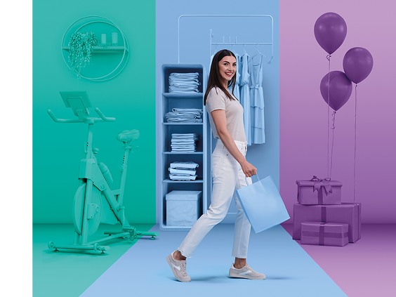 Smiling woman walking with a light blue shopping bag, surrounded by three colorful zones: a teal fitness area with a stationary bike, a blue wardrobe with folded clothes and dresses, and a purple gift area with balloons and presents