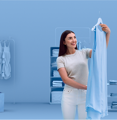 Smiling woman holding up a light blue dress in a modern, monochromatic blue-toned boutique with neatly organized clothing racks and shelves in the background